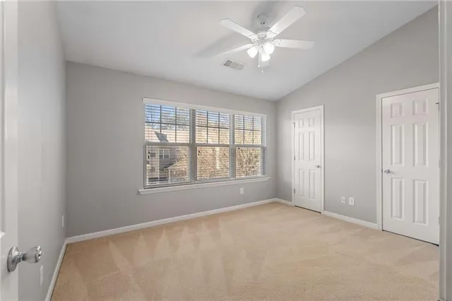 an empty room with chandelier fan and windows