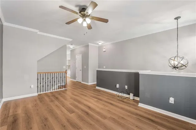 a view of an empty room with wooden floor and a ceiling fan