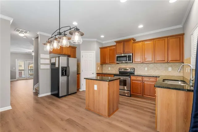 a kitchen with stainless steel appliances granite countertop a refrigerator a stove top oven a sink dishwasher and wooden floor