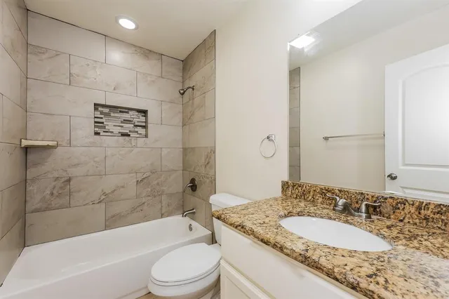 a bathroom with a granite countertop sink toilet bathtub and shower