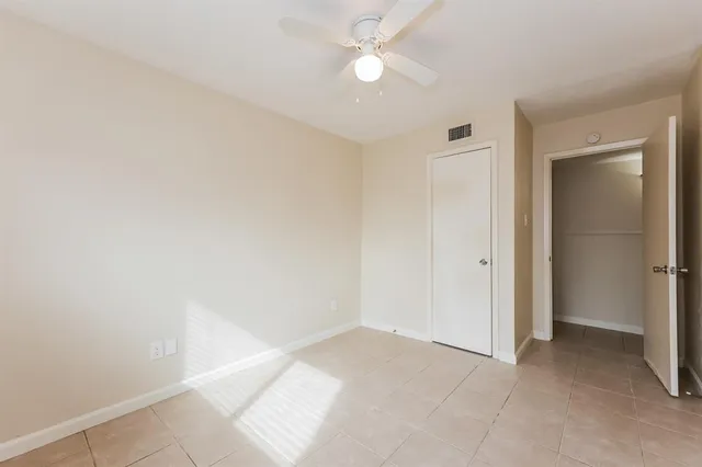 an empty room with closet and a ceiling fan
