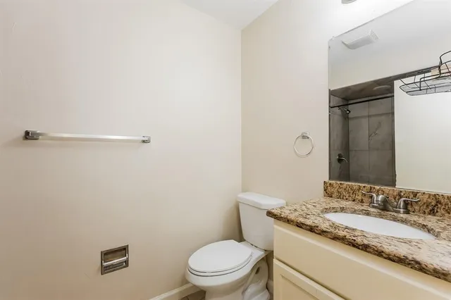 a bathroom with a granite countertop toilet and a sink