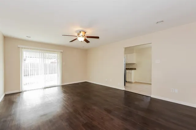 a view of an empty room with a window and wooden floor