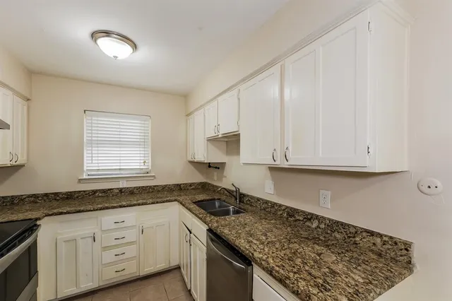 a kitchen with granite countertop a sink a stove and cabinets