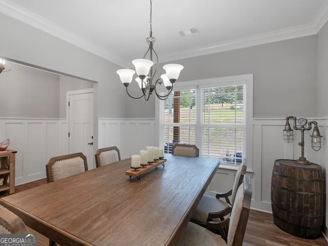 a dining room with wooden floor a chandelier a wooden table and chairs