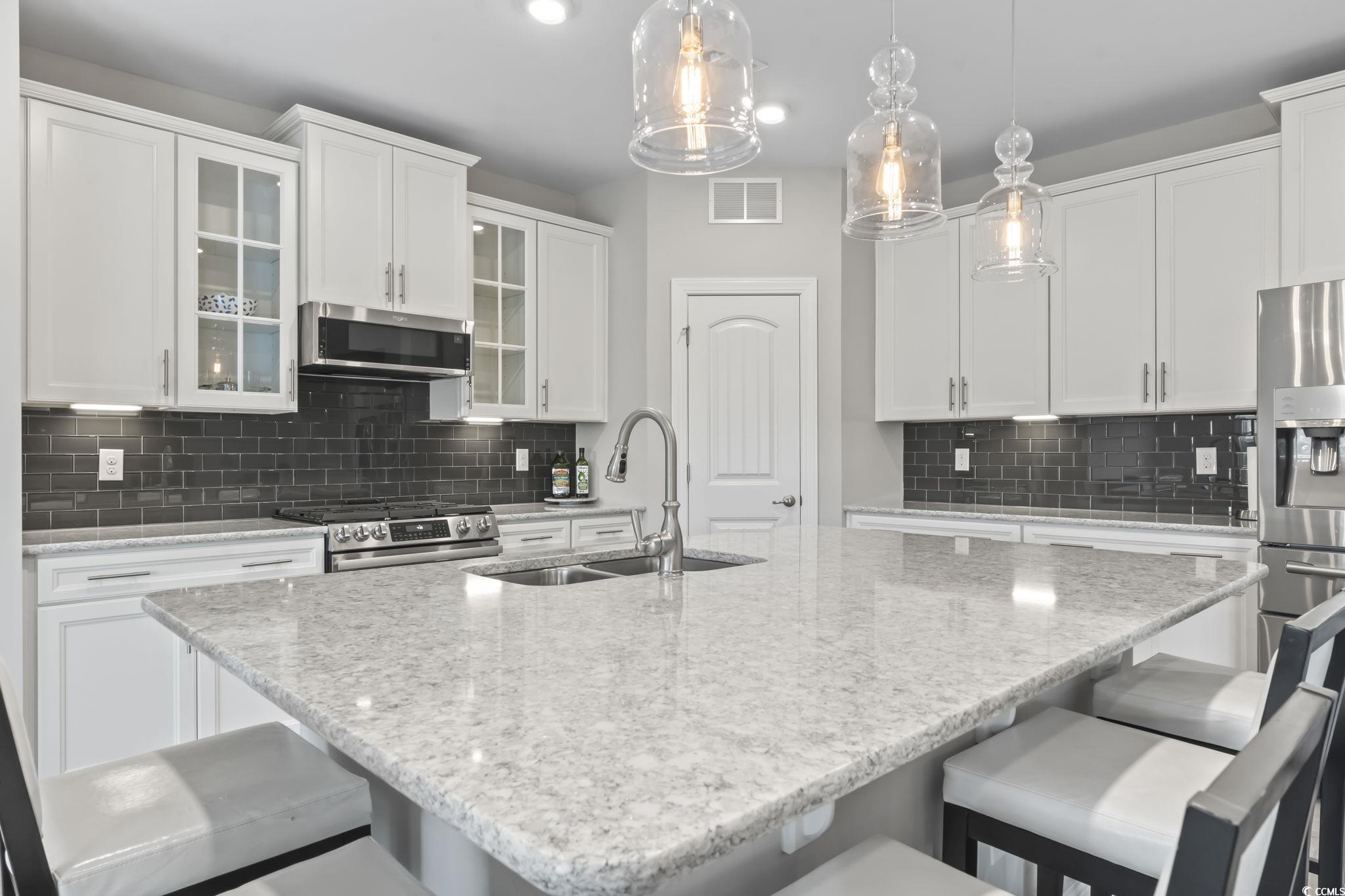 583 Hickman Street Surfside Beach, SC 29575 - Photo 22 of 40 Kitchen with a breakfast bar, glass insert cabinets, light stone countertops, and backsplash