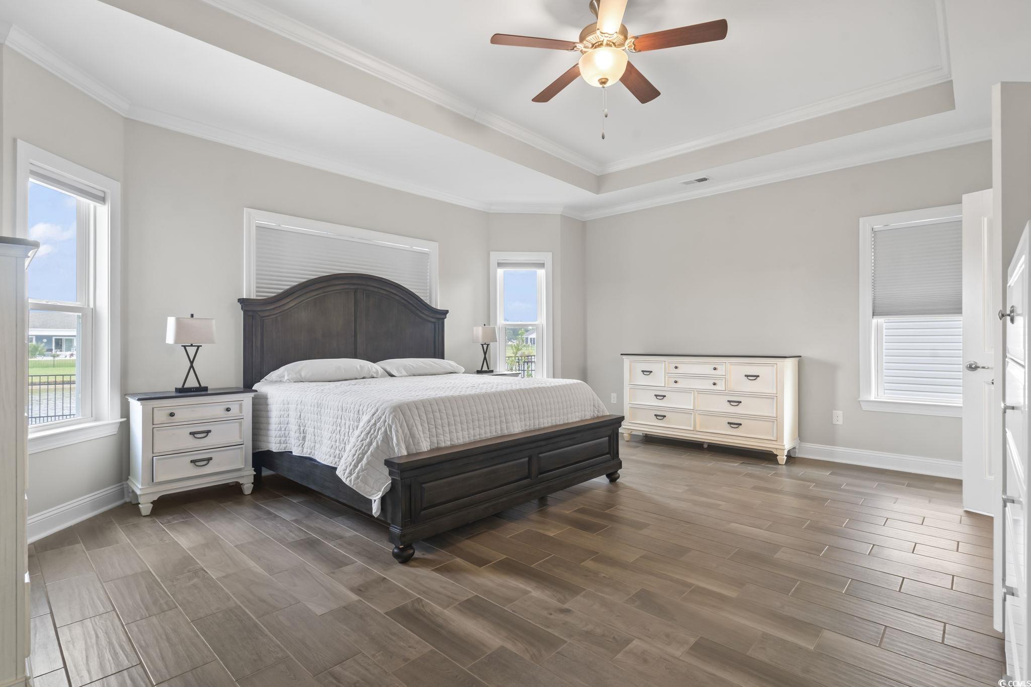 583 Hickman Street Surfside Beach, SC 29575 - Photo 24 of 40 Bedroom featuring a tray ceiling, multiple windows, dark wood-style floors, ornamental molding, and ceiling fan