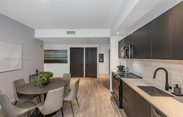 a kitchen with stainless steel appliances a sink a table and chairs