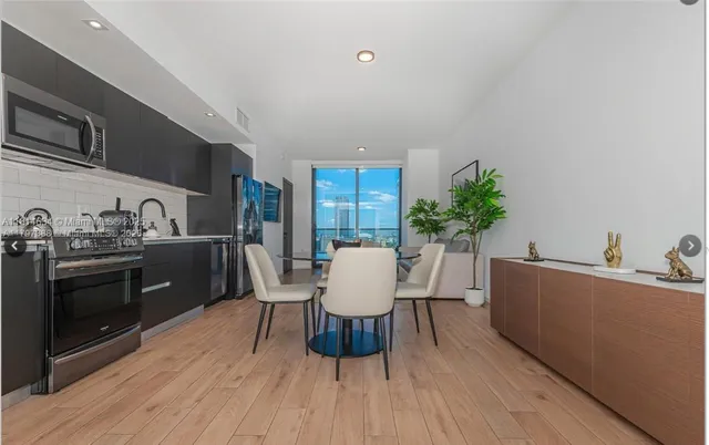 a living room with furniture a potted plant and kitchen view
