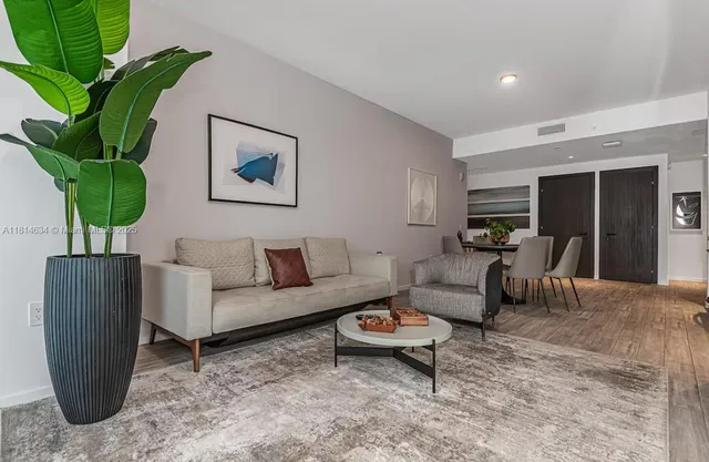 a living room with furniture a potted plant and a wooden floor