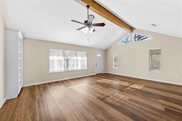 a view of an empty room with wooden floor and a window