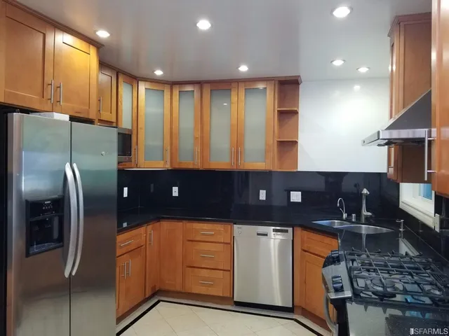 a kitchen with kitchen island granite countertop a refrigerator a stove and a sink