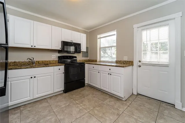a kitchen with granite countertop white cabinets and stainless steel appliances