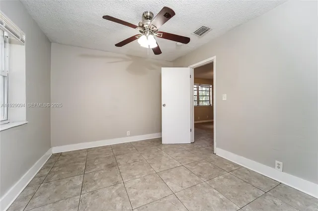a view of an empty room with window and chandelier fan