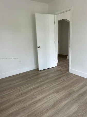 a view of an empty room with wooden floor and closet