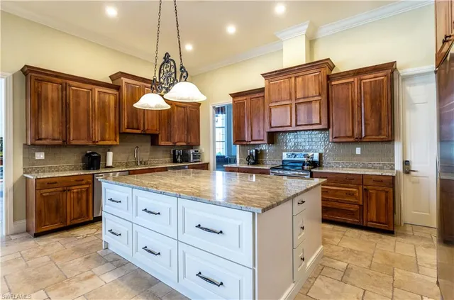 a kitchen with kitchen island granite countertop a sink counter top space appliances and cabinets