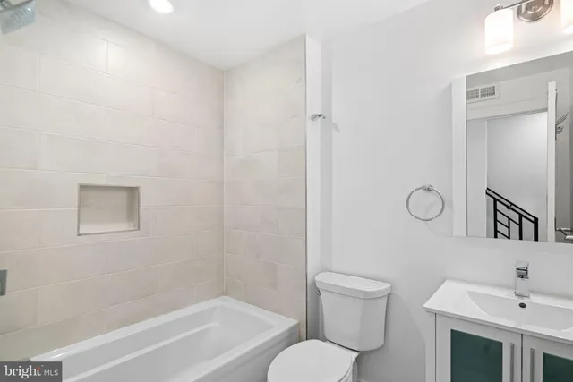 a bathroom with a toilet a sink a mirror and a bathtub