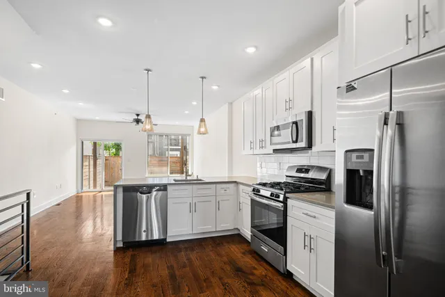 a kitchen with stainless steel appliances kitchen island granite countertop a stove a sink and white cabinets