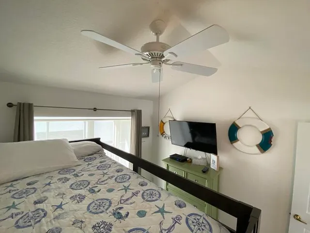 a bedroom with a bed and a flat tv screen on dresser