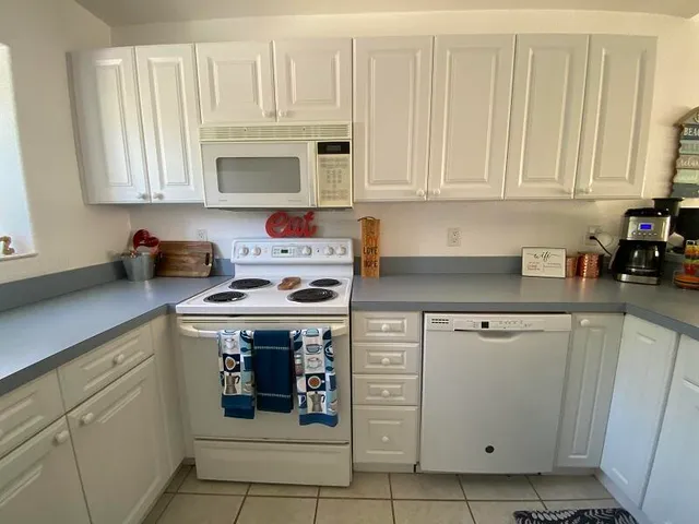 a kitchen with white cabinets and white appliances