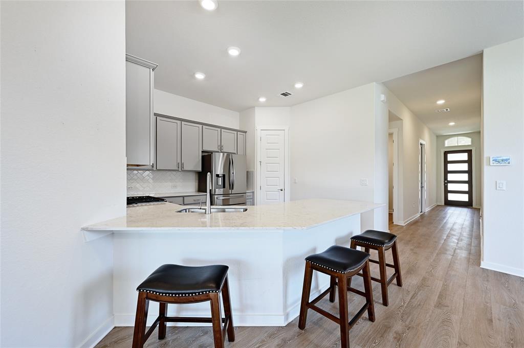 2133 Alamar Walk Leander, TX 78641 - Photo 6 of 25 a kitchen with kitchen island white cabinets and stainless steel appliances