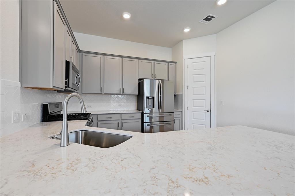 2133 Alamar Walk Leander, TX 78641 - Photo 8 of 25 a kitchen with stainless steel appliances granite countertop a sink refrigerator and microwave