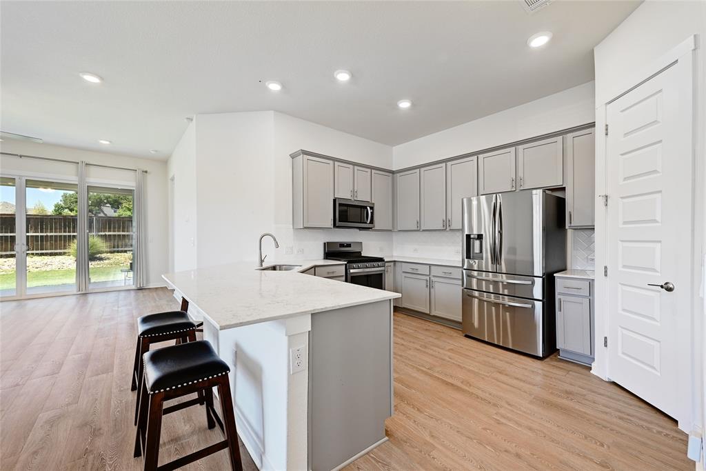 2133 Alamar Walk Leander, TX 78641 - Photo 9 of 25 a kitchen with granite countertop a refrigerator stove and sink
