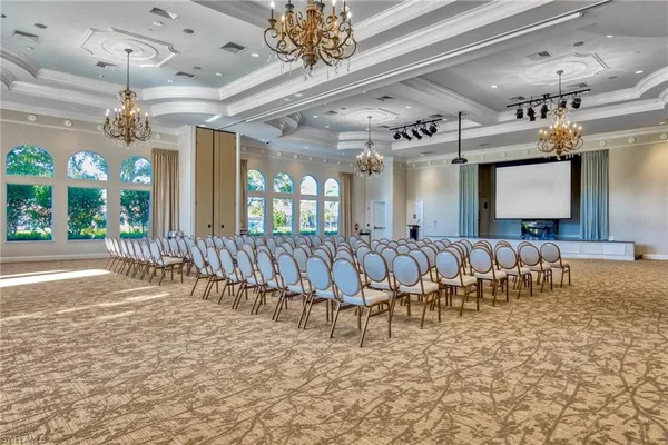 a large room with lots of white furniture and a chandelier