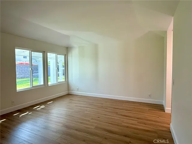 a view of a hallway with wooden floor and a bathroom