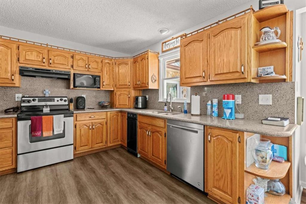 6058 Mt Zion Road Waco, GA 30182 - Photo 33 of 72 a kitchen with stainless steel appliances granite countertop a stove top oven a sink dishwasher and white cabinets with wooden floor