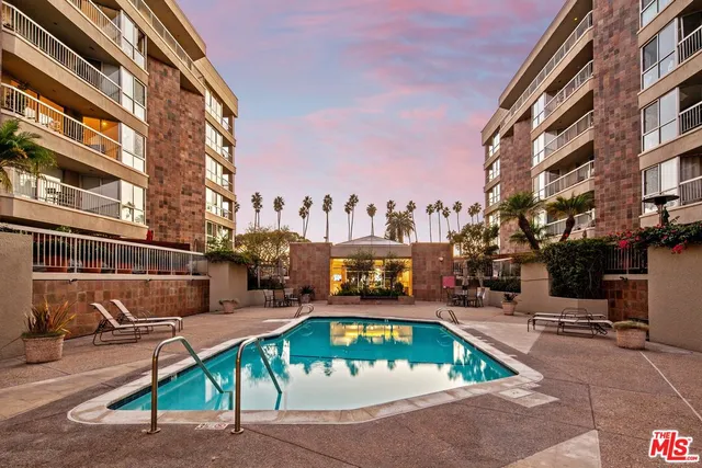 a view of a swimming pool with outdoor seating and buildings in the background