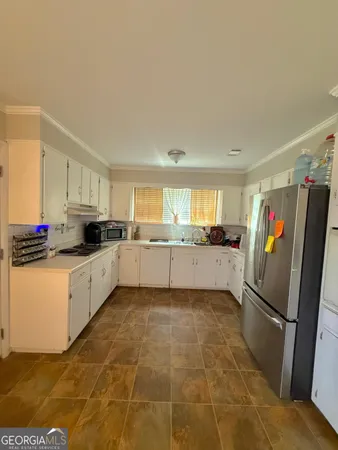 a kitchen with granite countertop a refrigerator and white cabinets