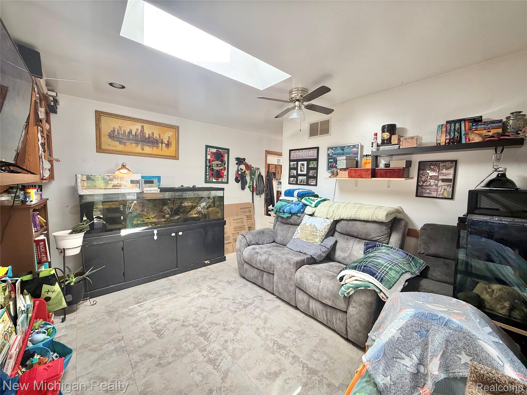 1054 Ransom Drive Flint, MI 48507 - Photo 12 of 27 Living area with a ceiling fan and a skylight