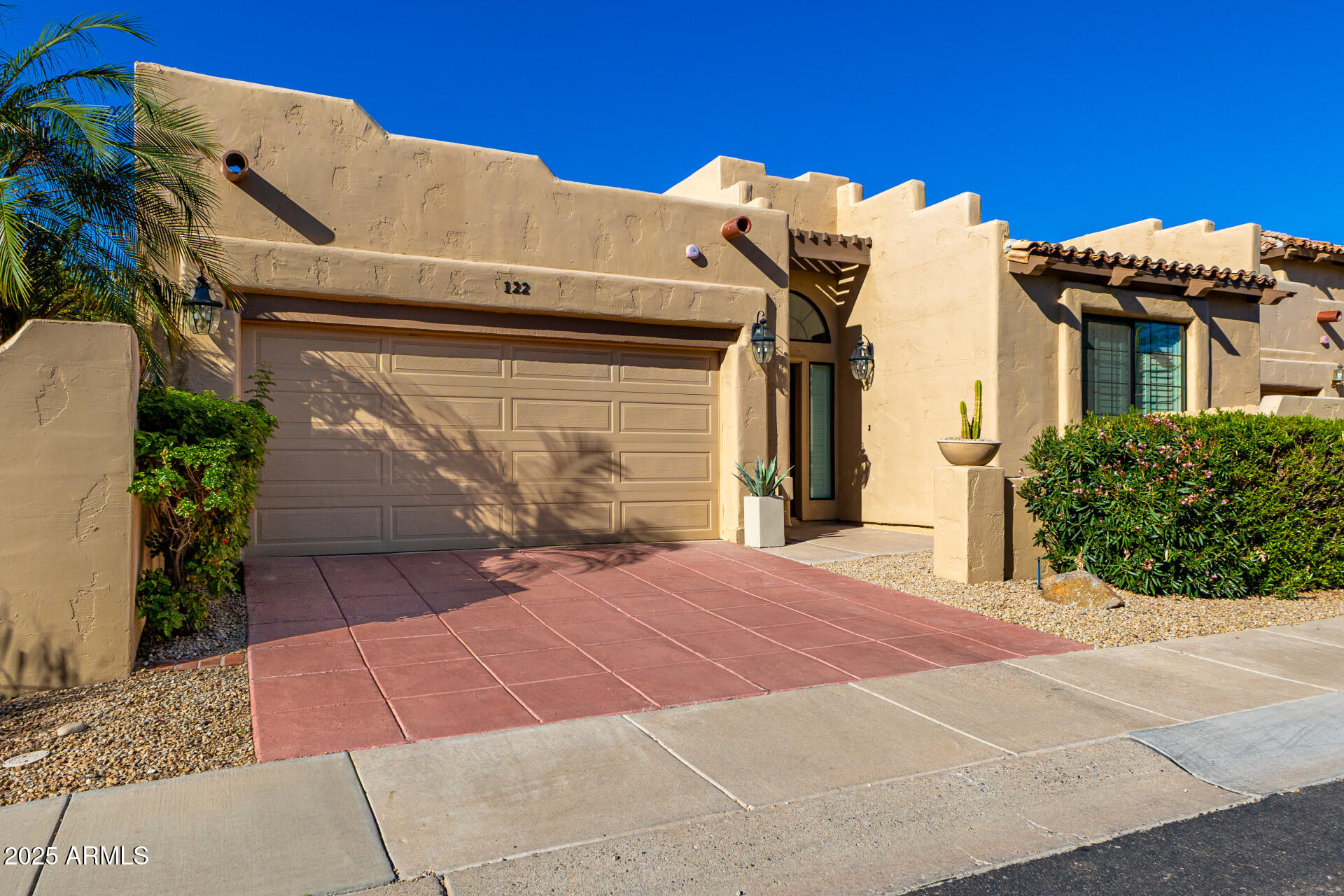 7955 East Chaparral Road, Unit 122 Scottsdale, AZ 85250 - Photo 1 of 29 a view of a white house with a small yard and potted plants