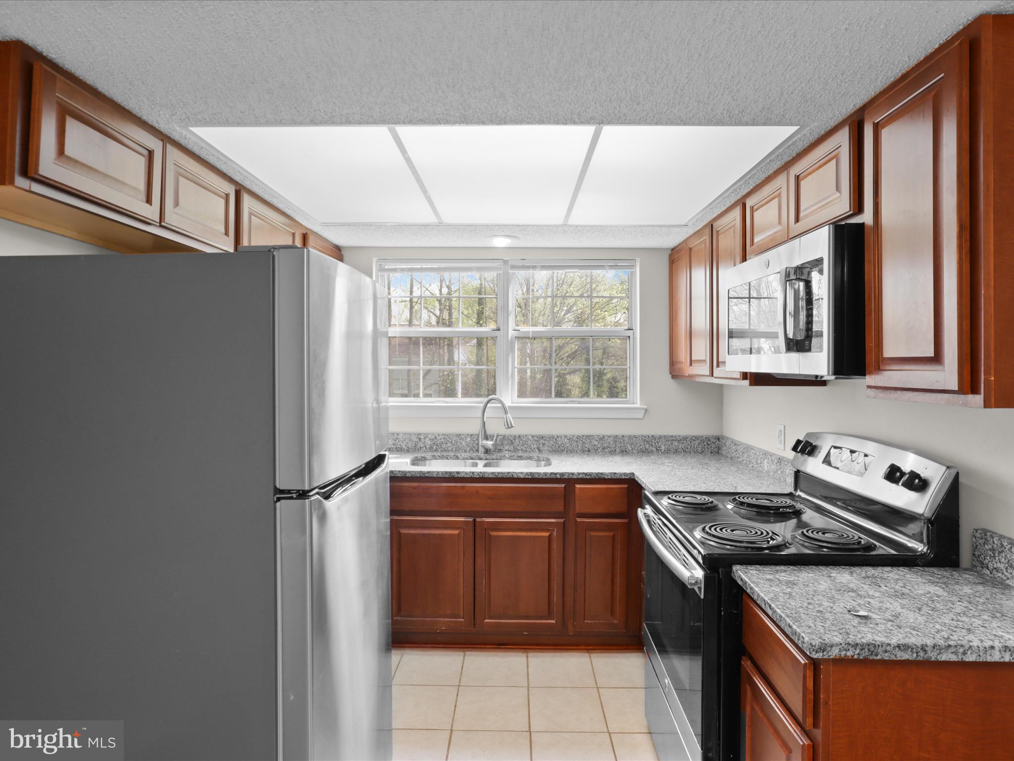 12008 Golf Ridge Court, Unit 356 Fairfax, VA 22033 - Photo 7 of 33 a kitchen with stainless steel appliances granite countertop a stove a sink and a refrigerator