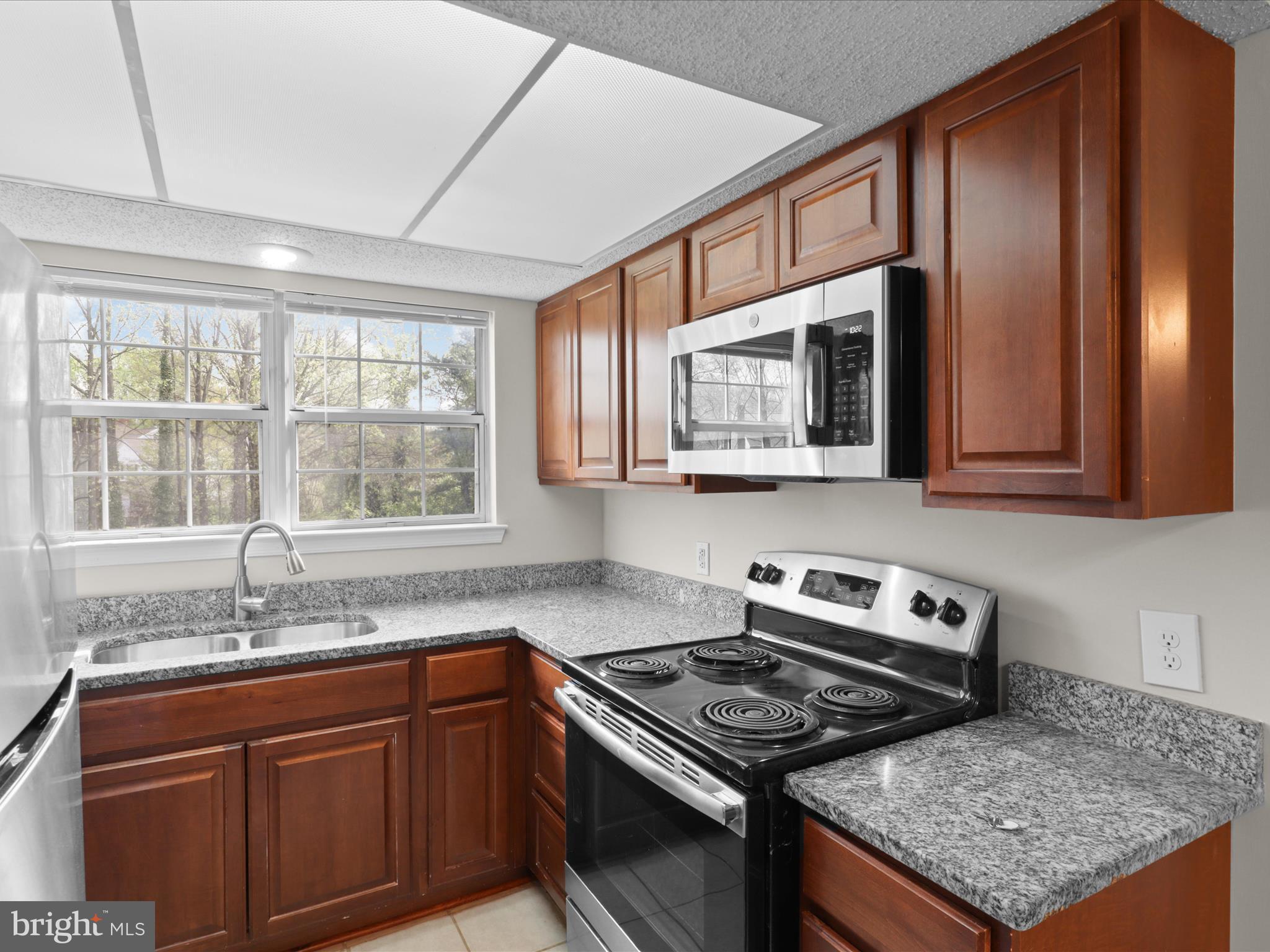 12008 Golf Ridge Court, Unit 356 Fairfax, VA 22033 - Photo 9 of 33 a kitchen with granite countertop a stove sink and microwave