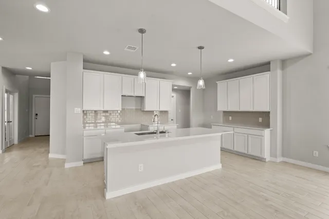 a large white kitchen with kitchen island a sink a center island stainless steel appliances and a cabinets