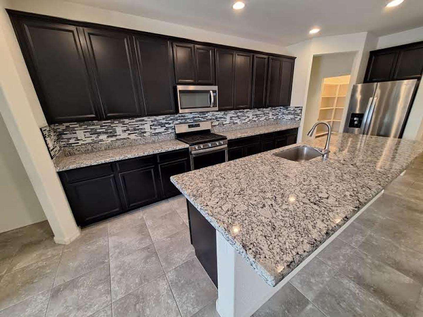 18541 West Mescal Street Surprise, AZ 85388 - Photo 10 of 31 a kitchen with stainless steel appliances kitchen island granite countertop wooden cabinets a sink and dishwasher