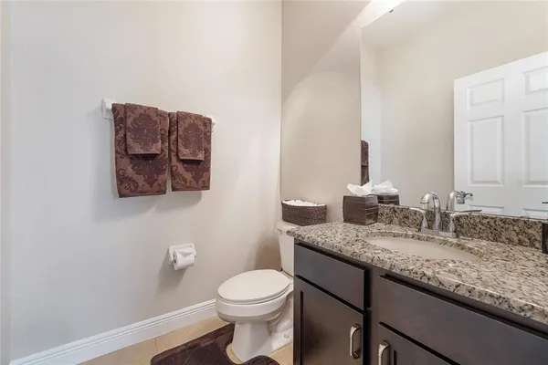 a bathroom with a granite countertop sink and a mirror with toilet