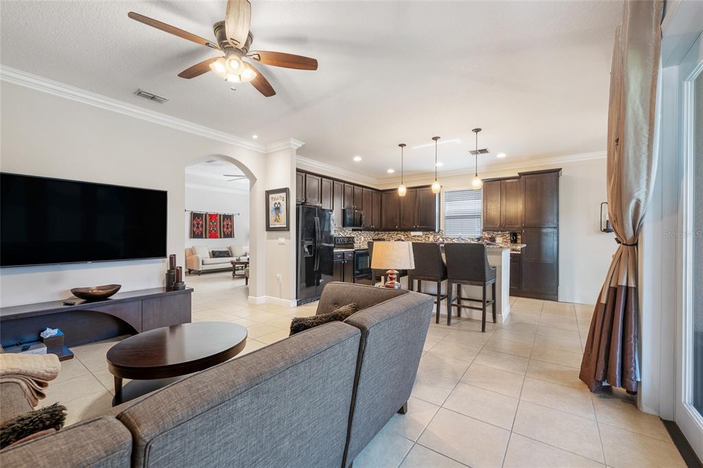 4436 Azure Isle Way Kissimmee, FL 34744 - Photo 15 of 35 a living room with furniture kitchen view and a flat screen tv