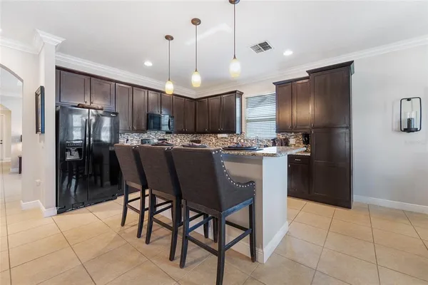 a kitchen with stainless steel appliances kitchen island granite countertop a refrigerator a stove a oven a sink with a dining table and chairs
