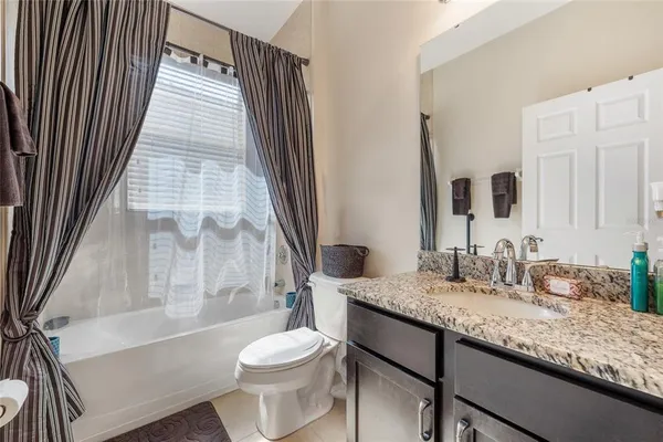 a bathroom with a granite countertop sink toilet mirror and bathtub
