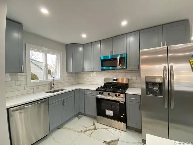 a kitchen with stainless steel appliances granite countertop a sink a stove a refrigerator and a microwave