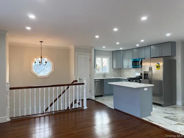 a kitchen with stainless steel appliances granite countertop a stove top oven a refrigerator with white cabinets and wooden floor