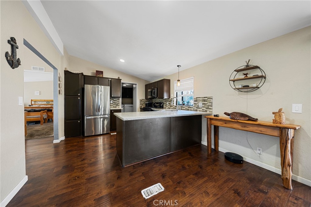 34437 Tree Lane Wildomar, CA 92595 - Photo 10 of 42 a kitchen with stainless steel appliances granite countertop a refrigerator a sink a stove and white cabinets with wooden floor