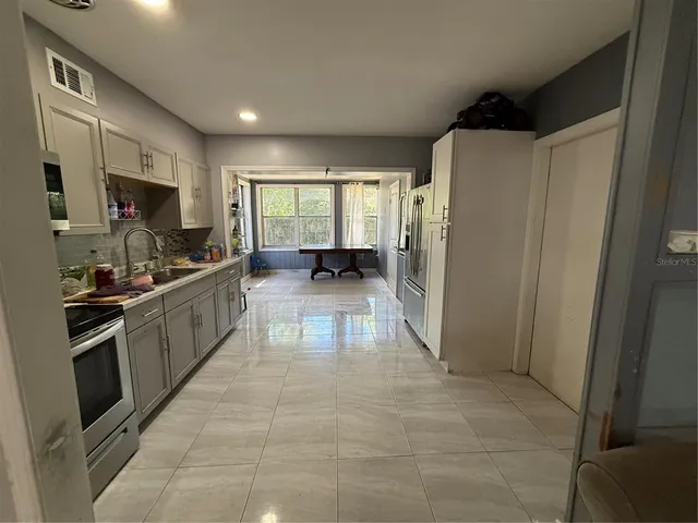 a large kitchen with stainless steel appliances a refrigerator and a stove top oven