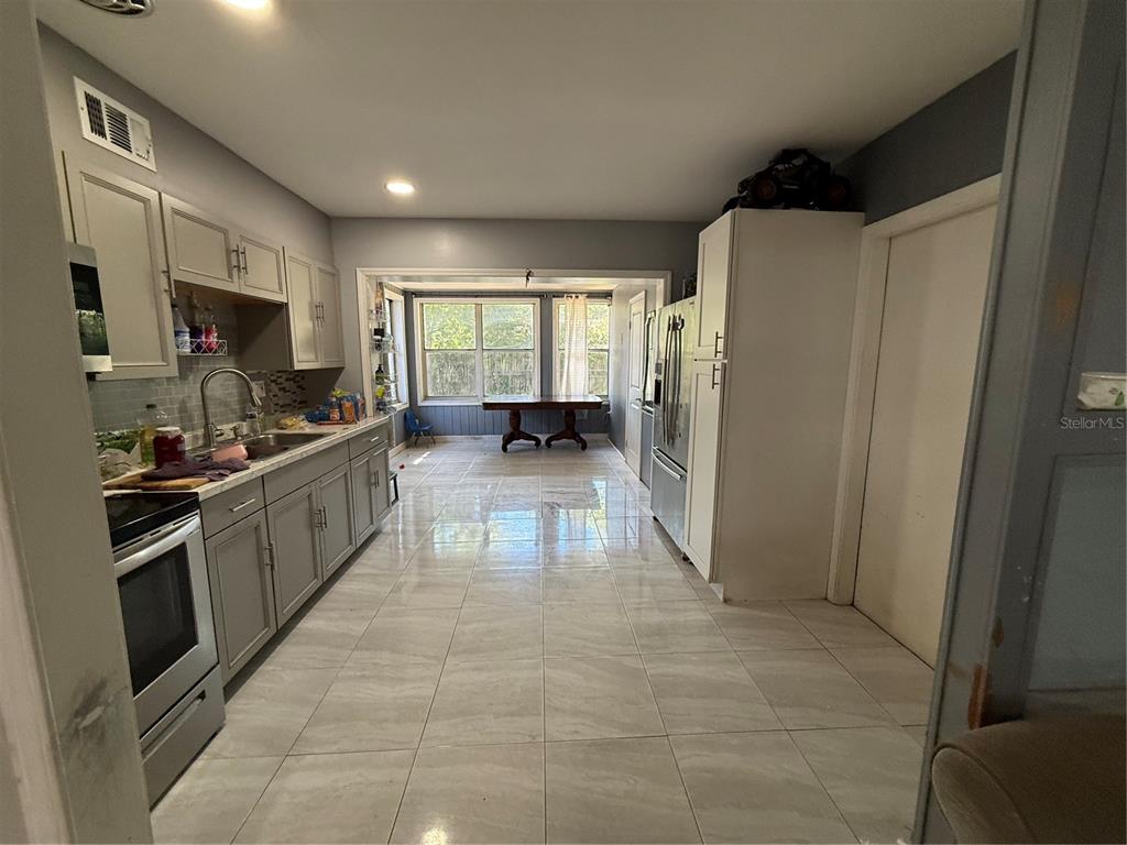 808 Derbyshire Road Daytona Beach, FL 32117 - Photo 17 of 23 a large kitchen with stainless steel appliances a refrigerator and a stove top oven