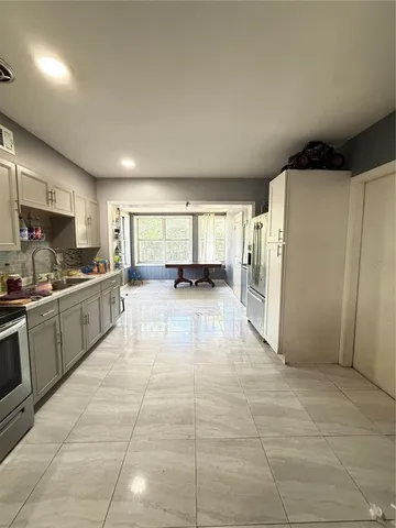 a large white kitchen with a sink and refrigerator