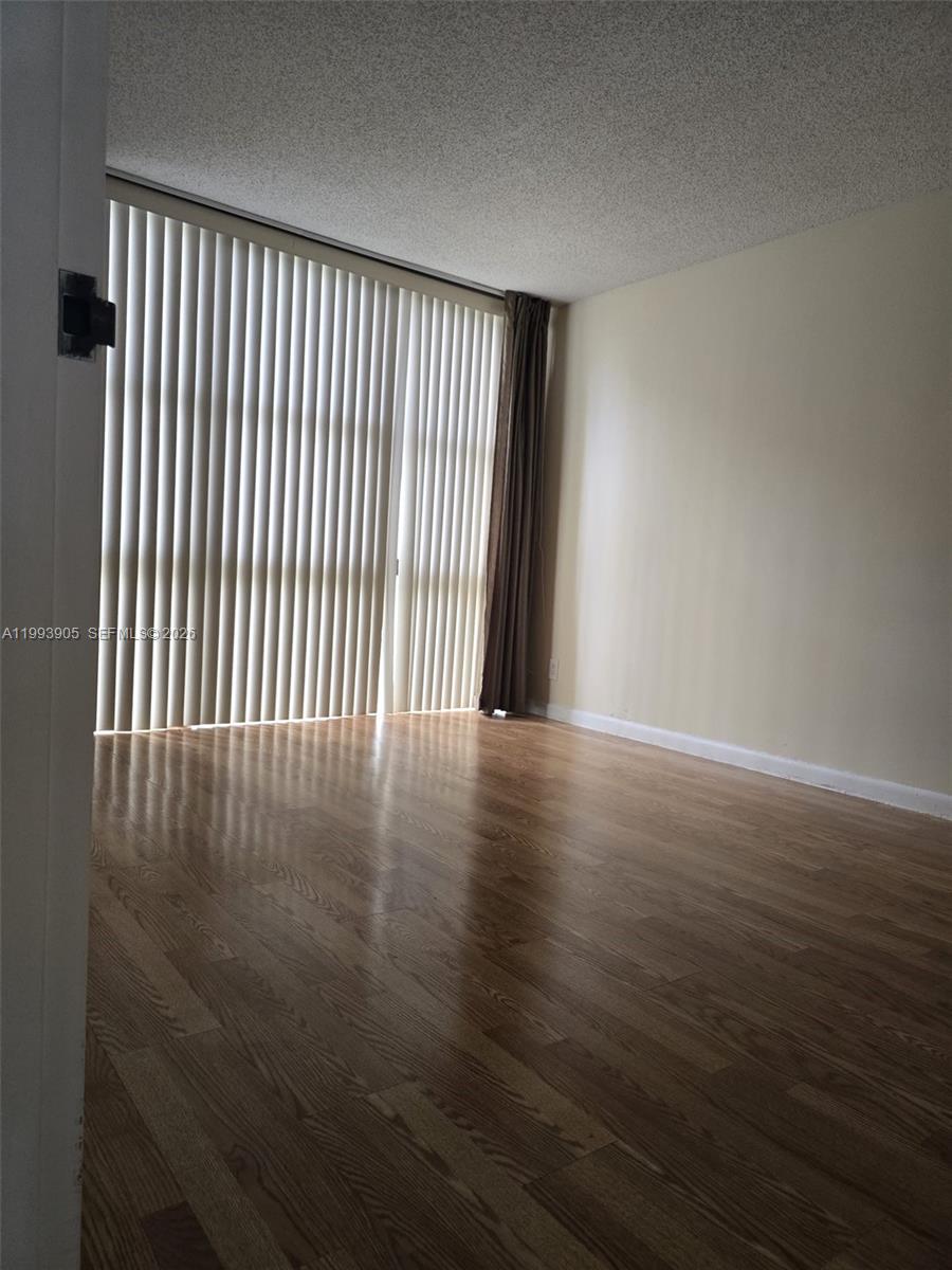 17021 North Bay Road, Unit 225 Sunny Isles Beach, FL 33160 - Photo 11 of 24 an empty room with wooden floor and windows