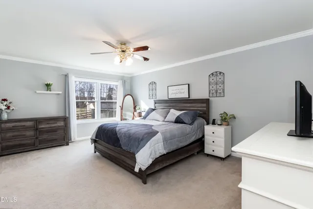 a spacious bedroom with a bed and a flat tv screen on dresser